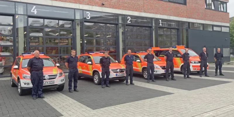 Feuerwehrm&auml;nner stehen vor Feuerwehrautos.